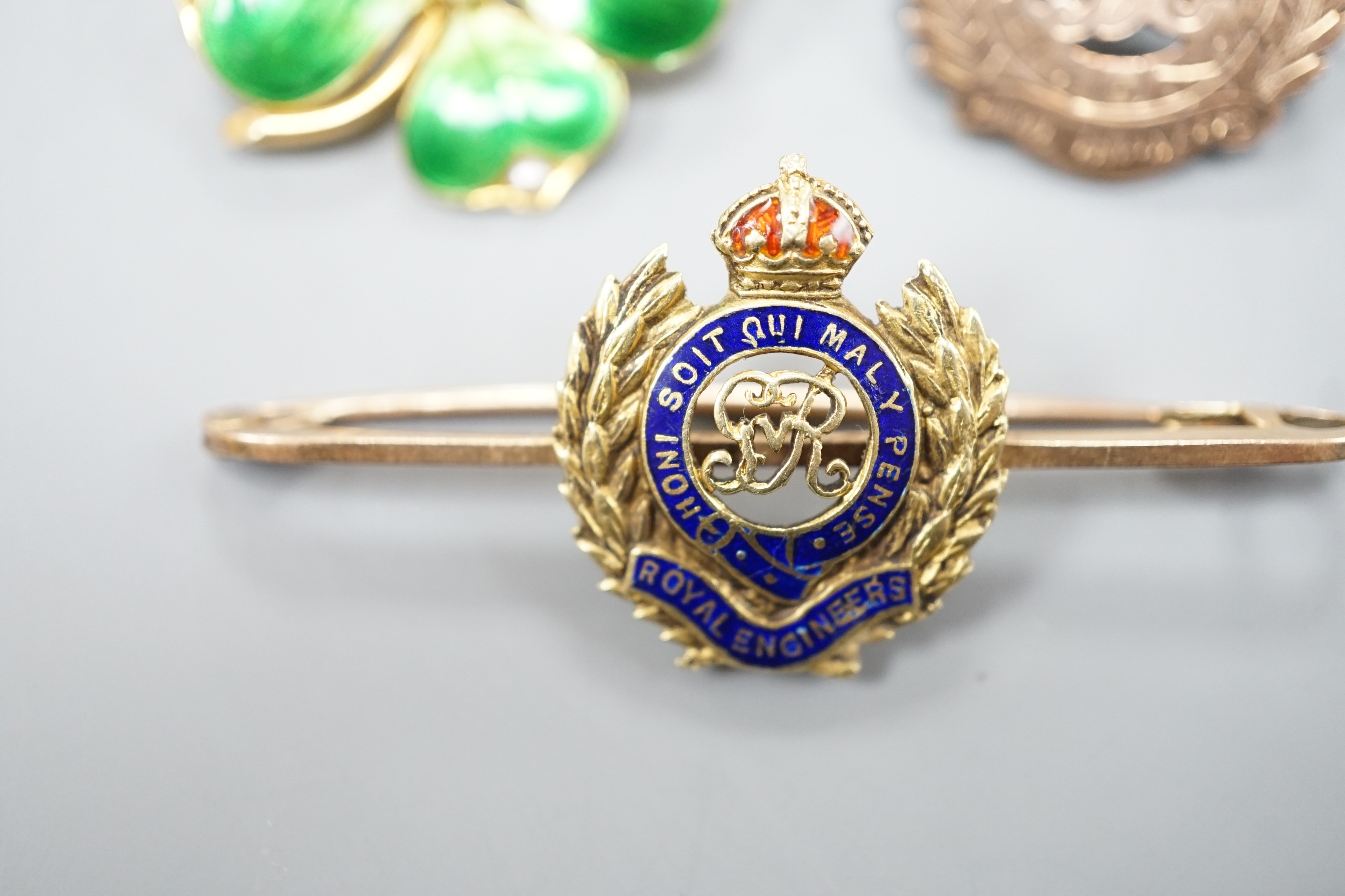 An early 20th century and two colour enamel set Royal Engineers sweetheart brooch, 5cm, gross 5.6 grams, an 18ct, seed pearl and green enamel clover brooch, 26mm, gross 6.2 grams and a sterling and yellow metal brooch.